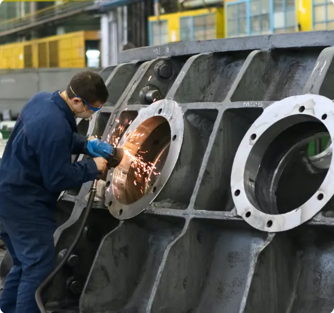 Technician grinding the housing of a large industrial unit