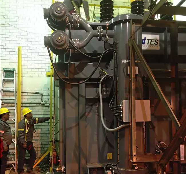 Personal de mantenimiento trabajando junto a un transformador industrial de gran tamaño