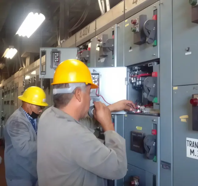 Technicians in hard hats working on a 480 V motor control center