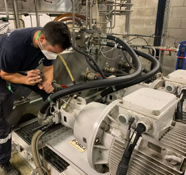 Técnico con cubrebocas reparando una unidad hidráulica industrial