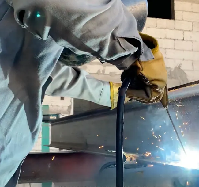 Soldador de ProCONECT con equipo de protección soldando una viga de acero